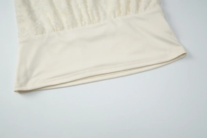 Close-up of cream lace patchwork and textured knit fabric on women's winter vest