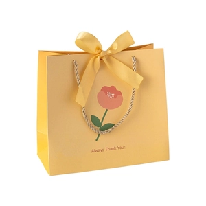 Yellow paper gift bag with tulip pattern and gold rope handle on white background