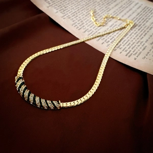 Collier ras du cou plaqué or avec émail noir et zircons posé sur du satin élégant