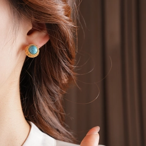 Close-up of vintage 18k gold plated turquoise stud earring worn on model ear
