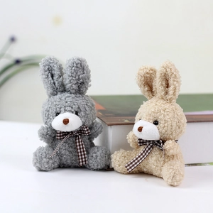 Close-up of gray and khaki plush bunny toys with plaid bows on a white table