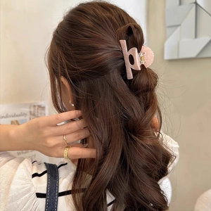 Pink speckled acetate claw clip securing a half-up hairstyle for women with a back view