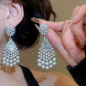 Close-up of pearl drop earrings with sparkling rhinestones worn on the earlobe