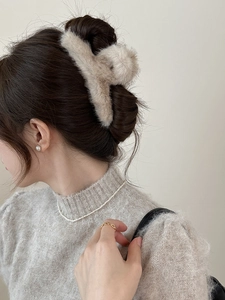Pince à cheveux en fausse fourrure beige sur cheveux bruns avec perles élégantes