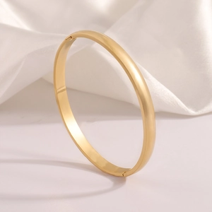 Close-up of minimalist gold-plated stainless steel bangle featuring a hinged clasp design