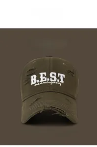 Detail of distressed olive green baseball cap with white embroidered letters and frayed edges
