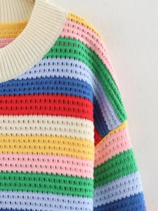 Gros plan du pull en maille crochetée à rayures arc-en-ciel montrant les coutures