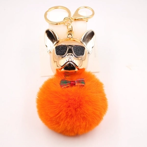 Dettaglio portachiavi bulldog francese con testa in metallo dorato e pompon arancione