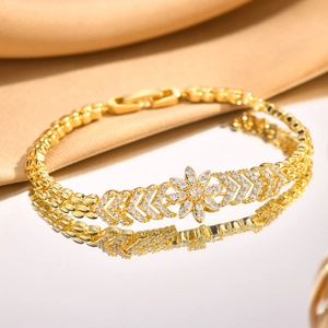 Detail of gold flower bracelet with zircon stones on a gold silk background