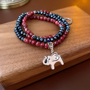 Detail of multi-layer beaded bracelet with blue faceted beads and silver elephant charm