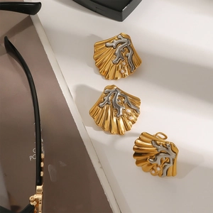 Gouden schelp oorbellen met zilveren koraal en kleine parels op een neutrale achtergrond