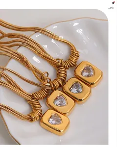 Detail of gold snake chains with rectangular heart pendants on a shell plate