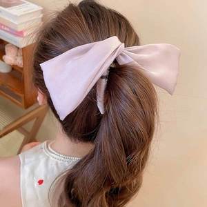 Détail d'une pince à cheveux avec nœud en satin rose pâle et oreilles de lapin sur cheveux