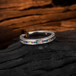 Macro shot of silver ring with colorful zircons set on a natural wooden background