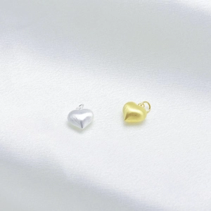 Detailed macro view of brushed gold and silver heart pendants on white silk background