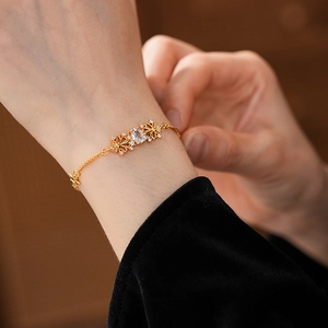Dettaglio del bracciale a fiore in oro con zircone centrale e design traforato fine