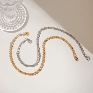 Detailed macro view of two-tone gold and silver stainless steel Cuban link anklets