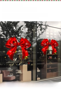Detail of red Christmas bow stickers with gold Merry Christmas text on a glass window