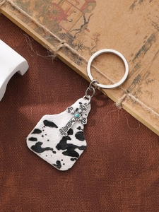 Detail of vintage cow print cowtag keychain with silver cross and turquoise beads