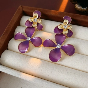 Macro shot of purple gradient flower stud earrings with crystals in a beige velvet box