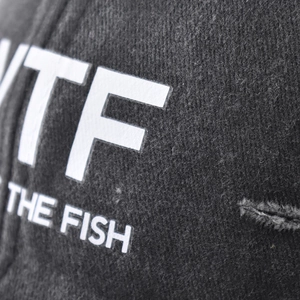 Close-up of cotton baseball cap featuring white WTF letters and THE FISH printed design