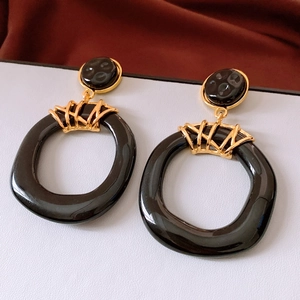 Close-up of vintage resin earrings with irregular hollow black rings and gold metal parts