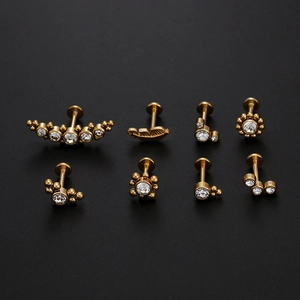 Detailed set of 8 gold titanium body piercings with cubic zirconia on black background