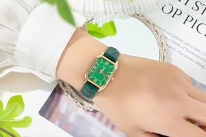 Close-up of elegant green rectangular watch dial with rose gold details and leather strap