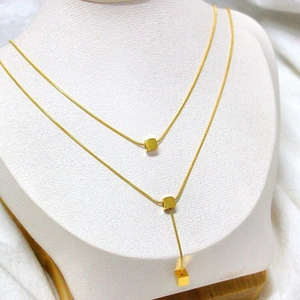 Golden double layer necklace featuring square cube pendants and sleek snake chains