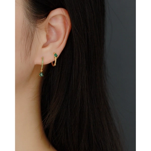 Detail of S925 silver gold twisted hoop earring with green emerald teardrop on model