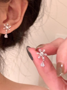 Détail de boucles d'oreilles flocon de neige argentées avec goutte de cristal