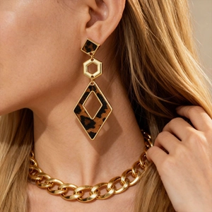 Close-up of geometric leopard print earrings with gold frames on a fashion model