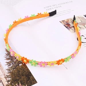 Close-up of orange daisy headband with embroidered flowers on a magazine background