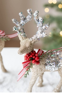 Macro shot of glittery gold reindeer statue with silver antlers and festive red bow detail
