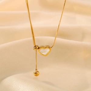 Golden heart shell pendant necklace on silk background with adjustable ball drop