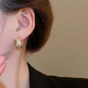 Detail of gold U-shaped hoop earrings with micro-pave cubic zirconia on a female model