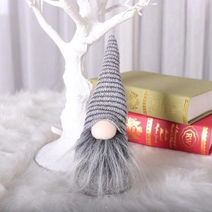 Grey knitted Christmas gnome plush decoration with long white beard in a cozy winter setting