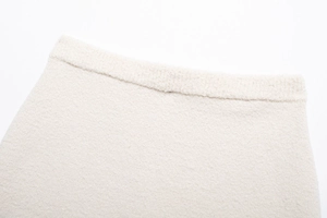 Detailansicht der cremefarbenen Tweed-Stofftextur und des Bundes am Rockteil