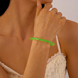 Détail d'un bracelet en acrylique vert émeraude translucide sur le poignet d'une femme