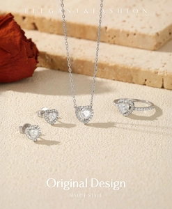 Macro detail of silver heart jewelry set featuring sparkling stones on stone with roses