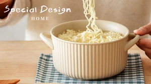 Close-up of noodles being lifted from a beige ceramic bowl with textured stripes