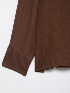 Detailed macro view of the dark brown floral textured fabric and neat stitching on sleeve