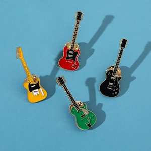 Detail of four colorful vintage electric guitar enamel pins on a blue textured surface