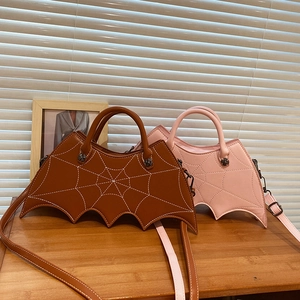 Detail of brown and pink bat-shaped PU leather handbags with spider web stitching