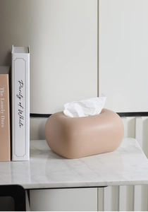 Détail d'une boîte à mouchoirs en céramique abricot mat sur table en marbre