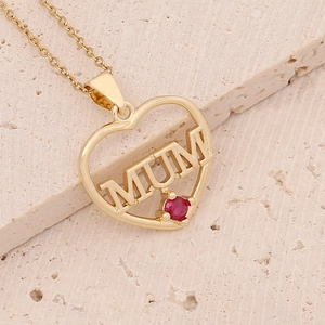 Detail of 18K gold plated heart necklace with red gem and MUM engraving on stone surface