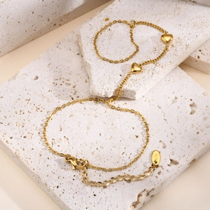 Close-up of golden stainless steel heart chain on stone with K18 engraved tag
