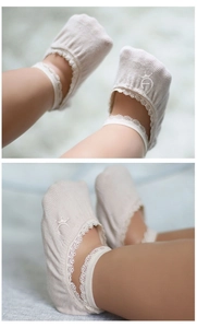Close-up of beige baby cotton socks with elegant lace trim and Mary Jane style ribbon ties