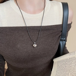 Detail view of a silver 3D heart pendant necklace worn with a minimal wax cord
