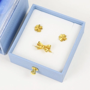 Elegant gold flower earrings and bow ring set displayed in a blue jewelry gift box
